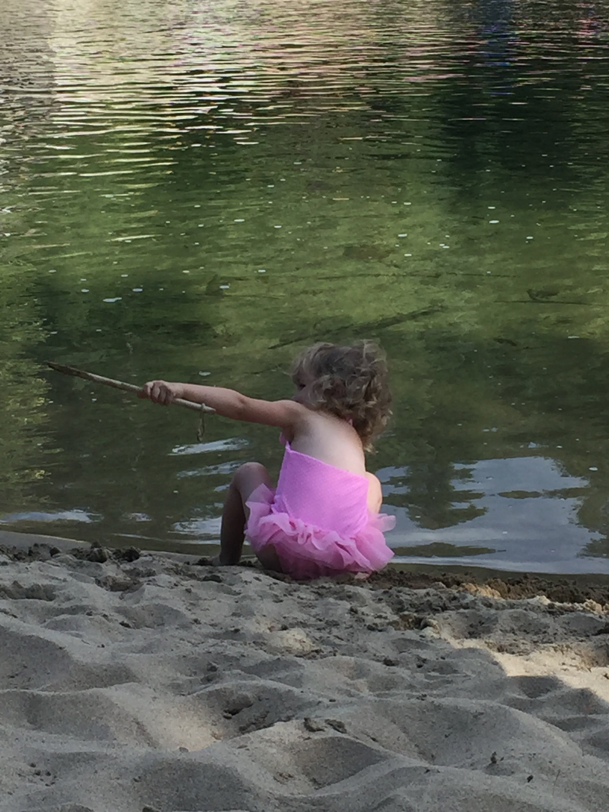 Child in a pink dress playing by in the kettle river.