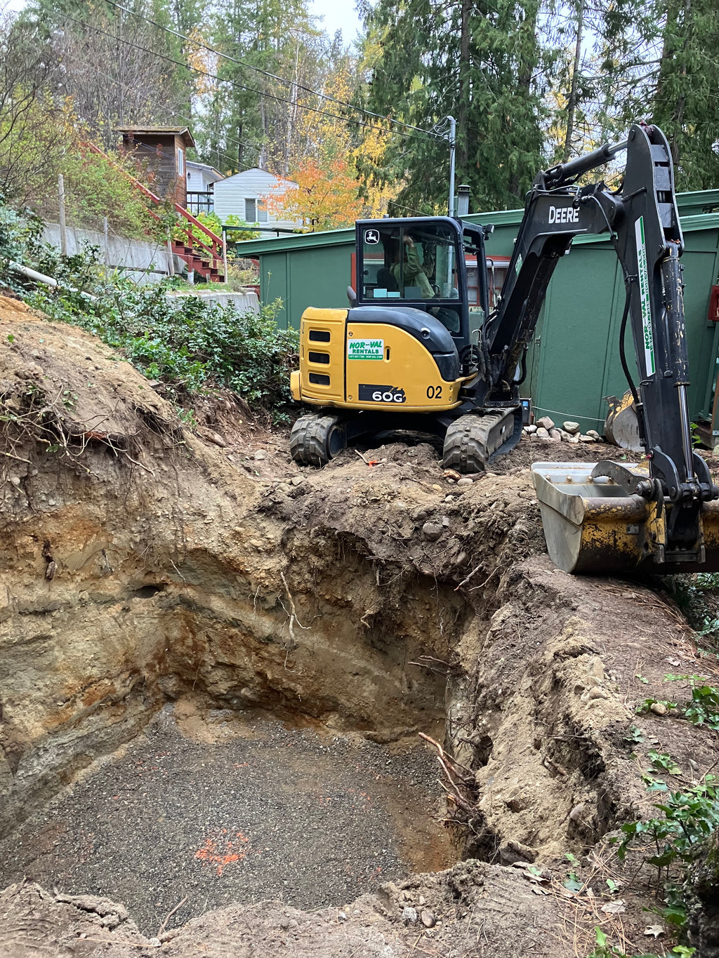 Excavator digging a hole for a wastewater treatment plant install.