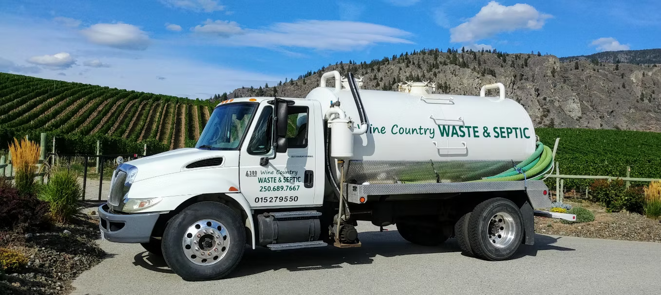 Waste and septic truck with 'One Country Waste & Septic' branding parked on a road with a scenic background.